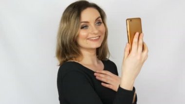 Bir akıllı telefonda bir selfie alır ve beyaz bir arka plana karşı kendini hayran siyah bir elbise güzel bir genç seksi zarif kadın portre
