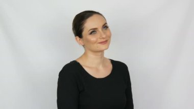 Güzel genç seksi kadın siyah elbise onaylayarak sevgi ile nazikçe ve gülümseyerek stüdyo beyaz bir arka planda bakıyor.