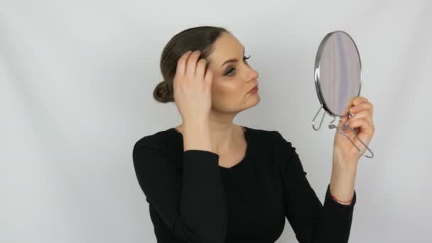 Portrait d'une belle jeune femme qui regarde dans un grand miroir rond sur fond blanc dans le studio — Video