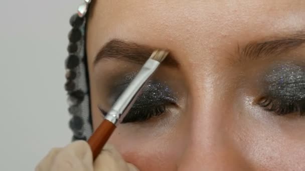 Profesionální make-up. Dívčí model kreslí obočí zvláštním kartáčem na obočí. Zakouřené kouřné oči. — Stock video