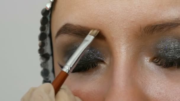 Trucco professionale di alta moda. Il modello di ragazza disegna sopraccigli con una spazzola di sopracciglio speciale. Occhi fumosi alla moda . — Video Stock