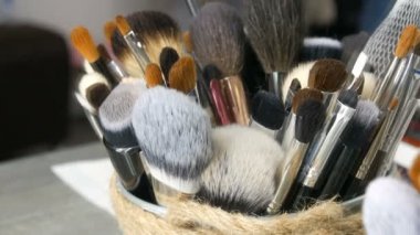 Giyinme odasında masada makyaj için profesyonel Fırçalar ayarlayın. Moda endüstrisi. Sahne arkasında yüksek moda gösterisi. Makyaj sanatçısı bir fırça alır.