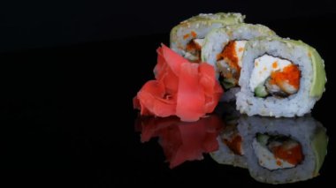 Yeşil Ejderha suşi rulo ve pembe zencefil. Somon, sebze ve avokado closeup suşi roll. Japonya Restoran Menü siyah bir arka plan ayna yüzeyinde. Studio Japon mutfağı