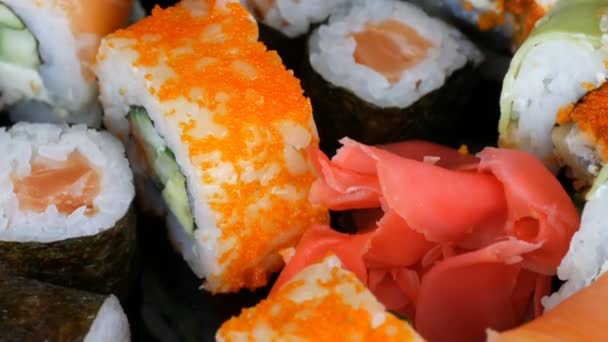 Wiele kolorowych sushi rolki zestawów i imbir na powierzchni lustra na czarnym tle. Dania kuchni japońskiej w studio — Wideo stockowe