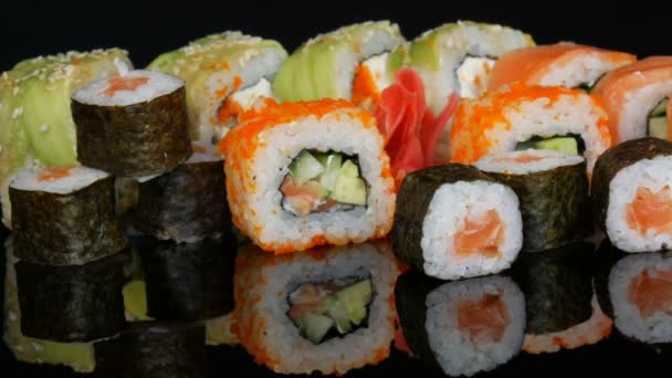 Různé barevné sushi rohlíky sad a zázvor na povrchu zrcadla na černém pozadí. Japonská kuchyně ve studiu — Stock video