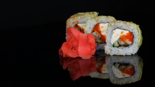青龙寿司卷和粉红色生姜。寿司卷与三文鱼, 蔬菜和鳄梨特写镜头。日本餐厅菜单在镜子表面在黑色背景。一室公寓内的日本料理 — 图库视频影像