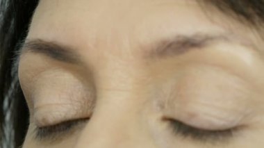 Özel bir fırça kaş gölgelerle kaşları boyar. Görünümü kapat. Profesyonel makyaj sanatçısı güzel mavi gözlü orta yaşlı yetişkin kadına makyaj yapıyor.