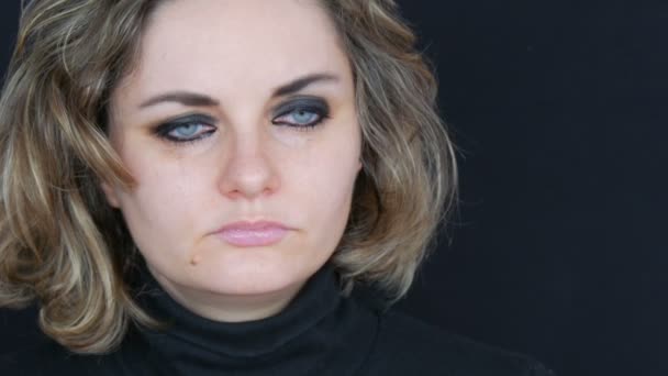 Schöne junge unglückliche Frau weint und wäscht Make-up ab. echte Tränen rinnen auf das Mädchengesicht, das in hysterischer Verzweiflung in einer schwarzen Jacke vor schwarzem Hintergrund schreit, Gesicht Nahaufnahme — Stockvideo