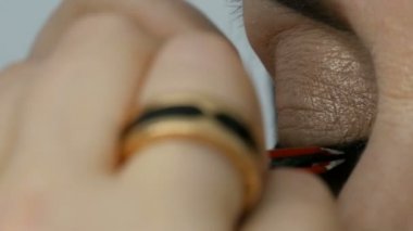 Profesyonel makyaj sanatçısı bir yetişkin orta yaşlı kadının mavi gözleri görünümü yakın yanlış kirpik sopa