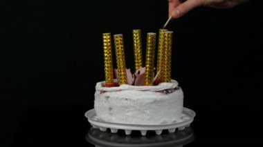 Womens üzerinde krem ve Hindistan cevizi gevreği ile süslenmiş kiraz reçel ile güzel bir şık tatlı taze beyaz kek üzerinde hafif mumlar eller. Siyah arka planda Doğum günü pastası.