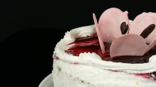 Beautiful stylish sweet fresh white cake with cherry jam decorated on top with cream and coconut chips rotates on a black background. — Stock Video