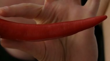 Bayan eller siyah arka plana karşı kırmızı Chili Peppers dokunma