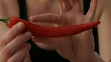 Bayan eller siyah arka plana karşı kırmızı Chili Peppers dokunma
