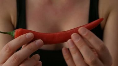 Bayan eller siyah arka plana karşı kırmızı Chili Peppers dokunma