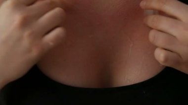 Kadın elleri siyah bir arka plana karşı siyah tişört onun meme cilt üzerinde cinsel buz küpleri sürtünme vardır. Kadın yaka için su damlaları aşağı doğru çalışır