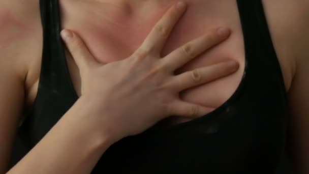 Womens hands scratching elastic skin of the chest in a black T-shirt on black background — Stock Video