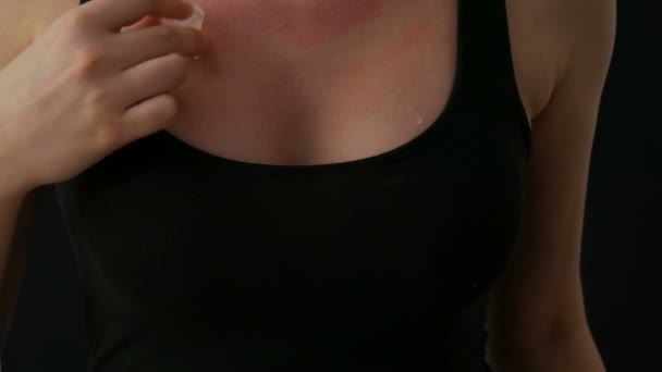 Ženy v lůně si potí kostky ledu přes kůži na prsou v černém tričku na černém pozadí. Kapky vody se sejí na výstřih — Stock video