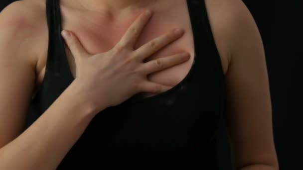 Női kezek karcolás elasztikus bőr a mellkas egy fekete póló, fekete háttér — Stock videók