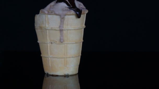Smältande glass på vilken häller chokladsirap sås på svart bakgrund — Stockvideo