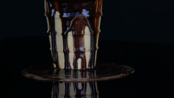 Crème glacée fondante sur laquelle verse de la sauce au sirop de chocolat sur fond noir — Video