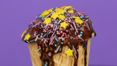 Açık mor arka planda uyku mavi renkli Sprinkles ile üst dekore vanilya dondurma döndürmek.