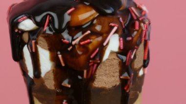 Çikolata sosu buzlanma pembe arka planda bir waffle fincan dondurma üzerinde akar