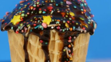 Çikolata sosu buzlanma ve renkli Sprinkles pembe arka planda bir waffle fincan dondurma üzerinde akar