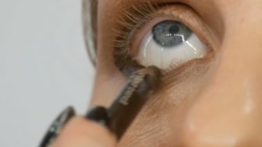 Profesyonel usta makyaj sanatçısı güzellik salonunda mavi göz modelinde kahverengi eyeliner kalem geçerlidir görünümü yakın