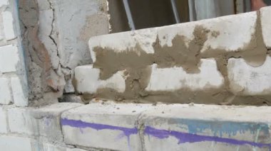 Erkek inşaatçı çimento ve ayakta duvara beyaz tuğla döşeme. Bina tuğlaları döşenen adamın elleri yakından görünümü