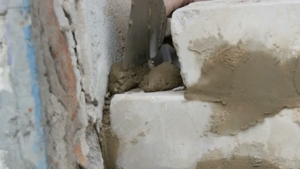 Constructor masculino colocando ladrillo blanco sobre cemento y pared de pie. Manos del hombre colocando ladrillos de construcción vista de cerca — Vídeo de stock