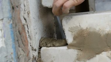 Erkek inşaatçı çimento ve ayakta duvara beyaz tuğla döşeme. Bina tuğlaları döşenen adamın elleri yakından görünümü