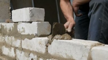 Erkek inşaatçı çimento ve ayakta duvara beyaz tuğla döşeme. Bina tuğlaları döşenen adamın elleri yakından görünümü