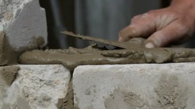 Erkek inşaatçı çimento ve ayakta duvara beyaz tuğla döşeme. Bina tuğlaları döşenen adamın elleri yakından görünümü