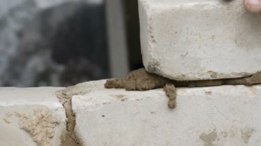 Erkek inşaatçı çimento ve ayakta duvara beyaz tuğla döşeme. Bina tuğlaları döşenen adamın elleri yakından görünümü