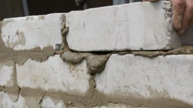 Erkek inşaatçı çimento ve ayakta duvara beyaz tuğla döşeme. Bina tuğlaları döşenen adamın elleri yakından görünümü