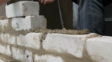 Erkek inşaatçı çimento ve ayakta duvara beyaz tuğla döşeme. Bina tuğlaları döşenen adamın elleri yakından görünümü