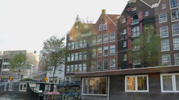 네덜란드 암스테르담 - 2019년 4월 22일: 저녁에 암스테르담 운하를 따라 걷습니다. 네덜란드의 오래된 주택입니다. 물 위에 있는 관광 보트의 창문에서 바라볼 수 있습니다. — 비디오