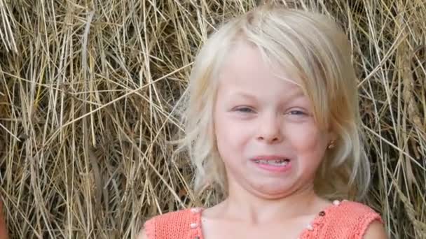 Retrato de una linda sonriente hace una cara y ríe rubia de ojos azules niña de siete años con una cara sucia niño en una calle fuera de la ciudad en un día de verano — Vídeos de Stock