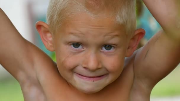Az öt éves szőke vicces piszkos gyermek lógott egy fa ága a vidéken egy nyári napon. Gyermek a természetben közelről kilátás szembenéz — Stock videók