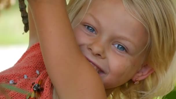 Yedi yıllık komik kirli çocuk kız sarışın yaz günü şehir dışında bir ağaç dalı üzerinde asılı — Stok video