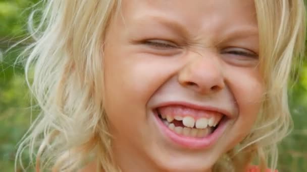 Retrato de una linda sonrisa y risa rubia de ojos azules niña de siete años con una cara sucia niño en una calle fuera de la ciudad en un día de verano — Vídeos de Stock