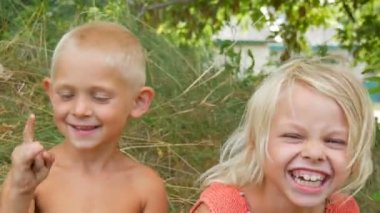 Komik kirli yüzleri çocuklar sarışın erkek ve kız kardeşi yüzleri gülmek gülmek ve bir yaz gününde doğada köyde eğlenmek