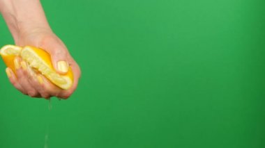 Sarı manikür ile Kadın el yeşil renk anahtar arka plan üzerinde yarım limon dışarı sıkar