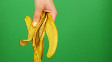 Sarı manikür ile Kadın el yeşil bir arka plan krom anahtar muz kabuğu tutar