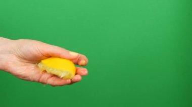 Sarı manikür ile Kadın el yeşil renk anahtar arka plan üzerinde yarım limon dışarı sıkar