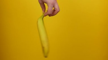 Sarı manikür ile Kadın el sarı arka plan üzerinde olgun bir muz meyve tutar