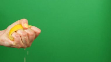Sarı manikür ile Kadın el yeşil renk anahtar arka plan üzerinde yarım limon dışarı sıkar
