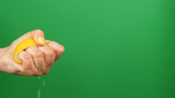 Vrouwelijke hand met gele manicure knijpt uit een halve citroen op groene Chroma Key achtergrond — Stockvideo