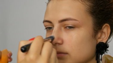 Genç oldukça kızıl saçlı genç kız yüzünde özel fırça ile kapatıcı uygulayarak