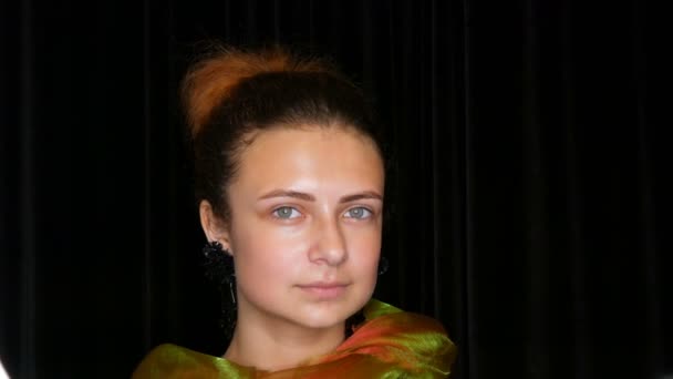 Jeune jolie adolescente aux cheveux roux en boucles d'oreilles noires et une écharpe verte pose sans maquillage dans un studio photo modèle — Video